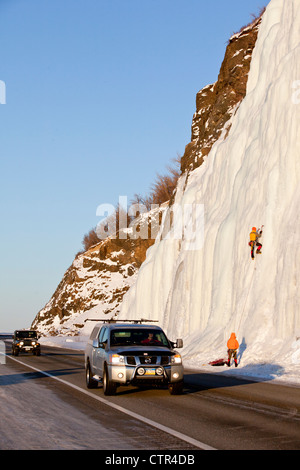 Gli scalatori di ghiaccio sulle cascate gelate accanto a Seward Highway come il traffico passa, centromeridionale Alaska, inverno Foto Stock