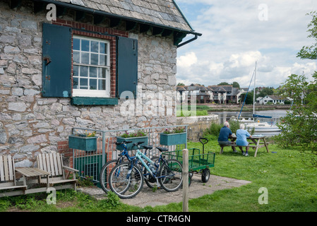 Vecchia serratura Keeper's Cottage, Exeter Ship Canal, biciclette e persone in giardino, Topsham, nei pressi di Exeter, la South Devon, Inghilterra, Regno Unito Foto Stock