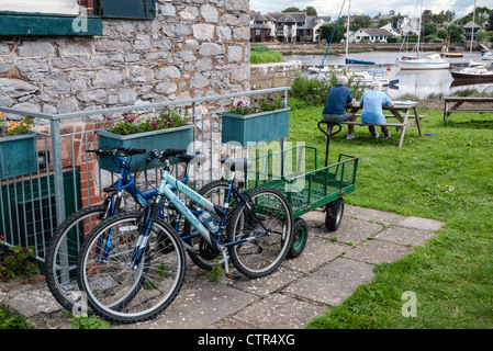 Vecchia serratura Keeper's Cottage, Exeter Ship Canal, biciclette e persone in giardino, Topsham, nei pressi di Exeter, la South Devon, Inghilterra, Regno Unito Foto Stock