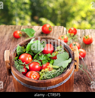 Canna di pomodori marinati su un vecchio tavolo di legno. Foto Stock