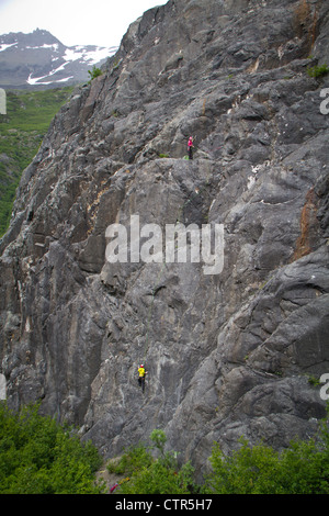 Femmina di rocciatore belaying uomo arrampicata su sciatto Peach sopra fiume Wosnesenki Kenai Mountains Kenai Peninsula centromeridionale Foto Stock