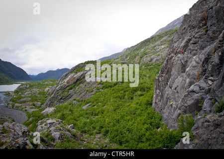 Femmina di rocciatore belaying uomo arrampicata su sciatto Peach sopra fiume Wosnesenki Kenai Mountains Kenai Peninsula centromeridionale Foto Stock