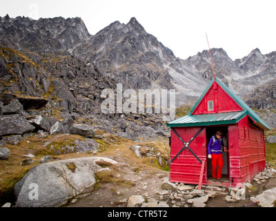 Uomo in piedi sulla porta della capanna di menta, Talkeetna montagne vicino Hatcher Pass, centromeridionale Alaska, Autunno Foto Stock