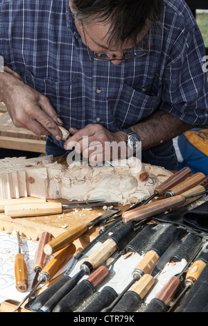 La tradizione intagliatore di legno di lavorare con utensili di intaglio in un festival a Oulx, Piemonte, Italia Foto Stock