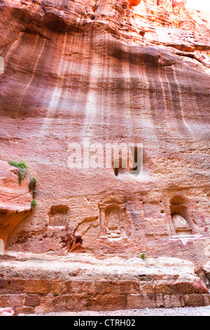 Piccoli antichi nabatei nicchie, santuari e intagli nella parete di Siq, Petra, Giordania Foto Stock