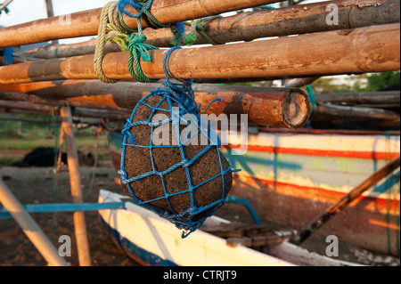 Stile Balinese tradizionale barca da pesca con una roccia utilizzata come ancoraggio. Il buttafuori le barche sono chiamati jukung. Foto Stock