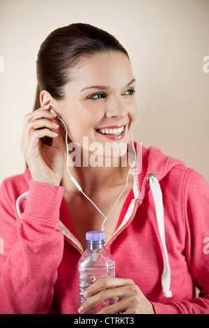 Una giovane donna che indossa abbigliamento fitness e gli auricolari per ascoltare musica Foto Stock