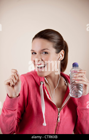 Una giovane donna che indossa abbigliamento fitness e gli auricolari per ascoltare musica Foto Stock