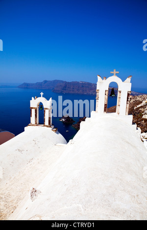 Oia - Santorini, isola greca, grecia, le campane della chiesa che si affaccia su caldera cicladi blu cielo nuvoloso Foto Stock