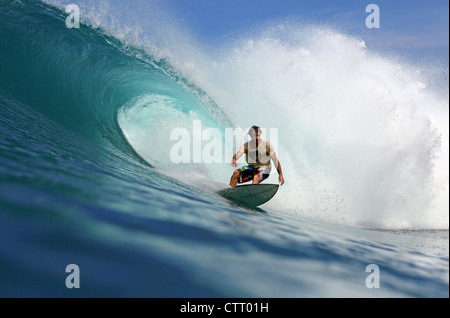 Surfista australiano in sella a una grande onda cava su un telecomando reef break sull'isola di Nias, Sumatra. Foto Stock