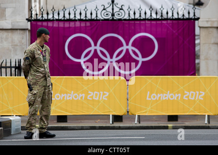 Un soldato dell'esercito britannico stand di guardia all'ingresso della pallavolo sede nel centro di Londra vicino al CIO ring logo sul giorno 4 del London 2012 Giochi Olimpici. Un ulteriore 1.200 militari sono utilizzati per proteggere le Olimpiadi del 2012 a Londra in seguito al mancato rispetto da parte di imprenditore di sicurezza G4S per fornire abbastanza guardie private. Il personale aggiuntivo sono stati redatti in mezzo continuando i timori che la sicurezza privata del contraente di manipolazione delle £284m contratto rimane un rischio per i giochi. Foto Stock