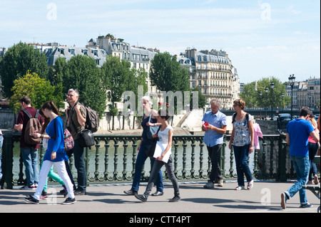 Parigi, Francia - i turisti a piedi sul ponte in una giornata di sole, l'Ile Saint Louis in background Foto Stock