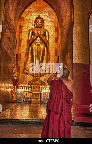Myanmar Birmania. Bagan. Monaco fotografare la statua del Buddha, Tempio di Ananda, coperte in teak in foglia oro. Foto Stock