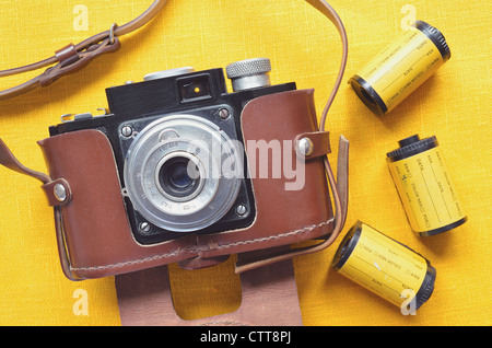 Vintage 35mm fotocamera a pellicola in custodia in pelle con rotoli di pellicola intorno; concentrarsi sul corpo della fotocamera Foto Stock