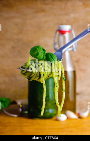 Spaghetti con pesto su una forcella e gli ingredienti in background Foto Stock