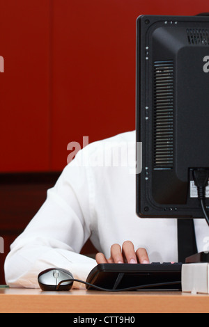 Un uomo che lavora con il computer in ufficio Foto Stock