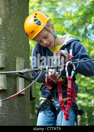 8 anno vecchia ragazza il suo fissaggio cavi di sicurezza in un parco di arrampicata a VIANDEN, Lussemburgo Foto Stock