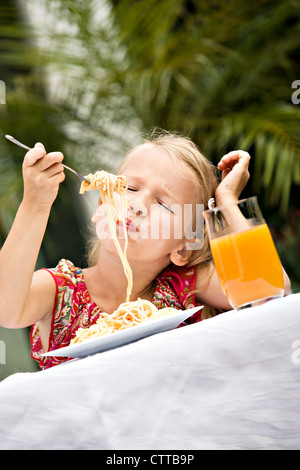 Ragazza Mangiare spaghetti in un giardino Foto Stock