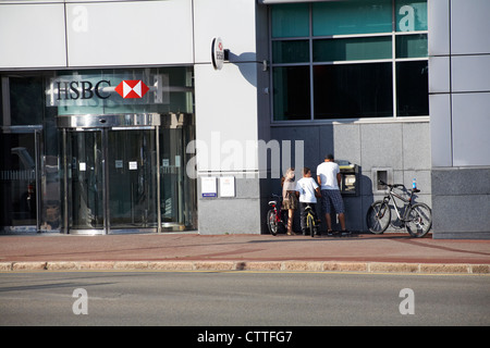 Famiglia con pushbikes utilizzando bancomat presso la banca HSBC a St Helier, Jersey, Isole del canale, Regno Unito nel mese di luglio Foto Stock