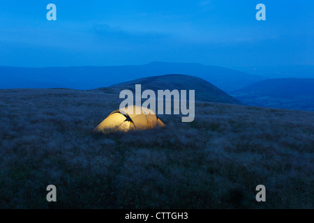 Campeggio selvaggio su Mynydd Troed durante la notte, con il nero montagne in distanza. Parco Nazionale di Brecon Beacons. La contea di Powys. Il Galles. Regno Unito. Foto Stock