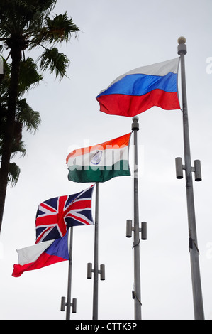 Quattro bandiere nazionali sulla bandiera poli battenti in una giornata di vento. Foto Stock