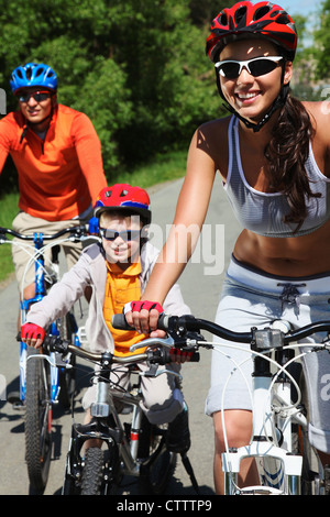 Ritratto di donna felice di fronte alla sua famiglia in sella per biciclette Foto Stock