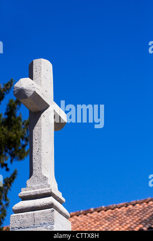 Croce di pietra contro un cielo blu in un cimitero francese. Foto Stock