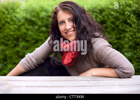 Ritratto di una donna sorridente nel parco in posa contro lo sfondo di boccole Foto Stock