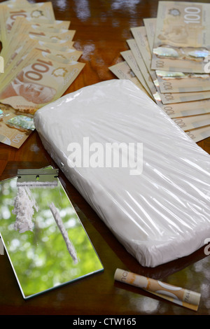 Grande borsa di cocaina e di coke linea con una lama di rasoio su specchio sul tavolo con denaro contante in canadian 100 fatture del dollaro Foto Stock