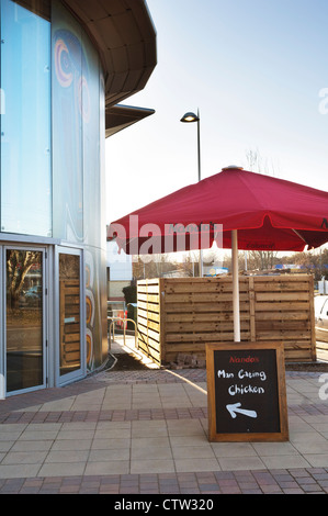 Una lavagna al di fuori di un Nando's restaurant con un gioco di parole dicendo che "l'uomo mangiare pollo". Foto Stock