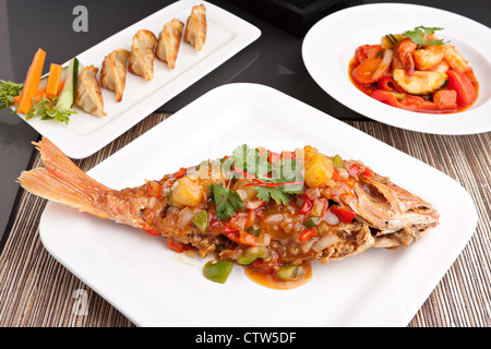 Preparato di fresco stile tailandese pesce intero red snapper cena con dolce e salato di gamberi e pan fritto gnocchi gyoza antipasto. Foto Stock