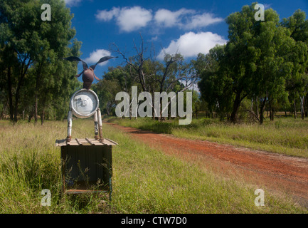 Scultura di mucca mailbox stradale realizzato in parte al di fuori della canna metallica con tipico rosso sporco la via che conduce alla proprietà Austra Queensland Foto Stock