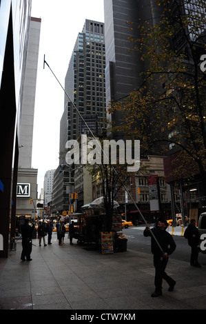 In autunno il marciapiede ritratto, alla settima Avenue, uomo con spatola telescopica facciata di pulizia Chase Bank, West 52nd Street, New York Foto Stock
