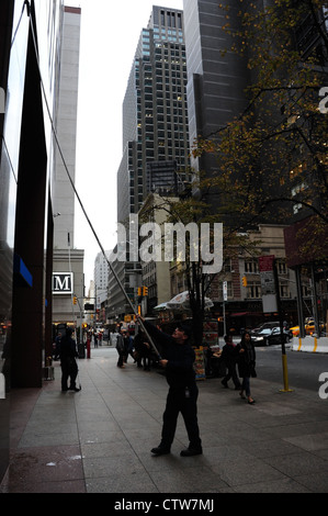 In autunno il marciapiede ritratto, alla settima Avenue, l'uomo con la spatola telescopica facciata di pulizia Chase Bank, West 52nd Street, New York Foto Stock
