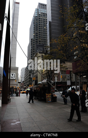 Mattina autunnale ritratto, verso la settima Avenue, l'uomo con la spatola telescopico in marmo pulizia Chase Bank, West 52nd Street, New York Foto Stock