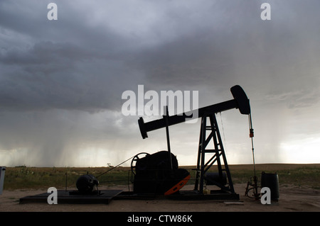 Un olio derrick continua a pompa durante un temporale pomeridiano vicino Ogallah, Kansas. Foto Stock