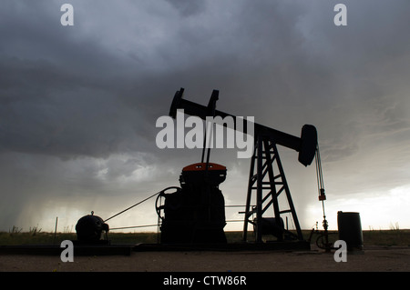 Un olio derrick continua a pompa durante un temporale pomeridiano vicino Ogallah, Kansas. Foto Stock