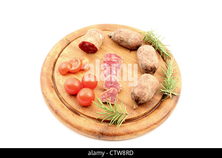 Carni con pomodori oltre il bordo di taglio e un rametto di rosmarino. Foto Stock