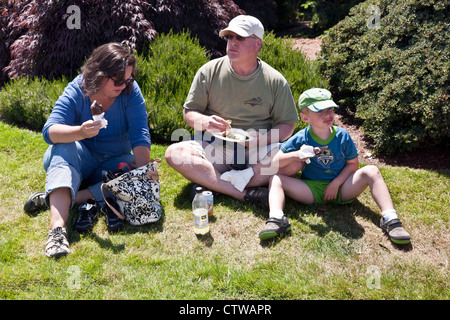 Famiglia Americana gode di picnic improvvisato sull'erba in bright sole estivo sabato al mercato degli agricoltori Edmonds Washington Foto Stock