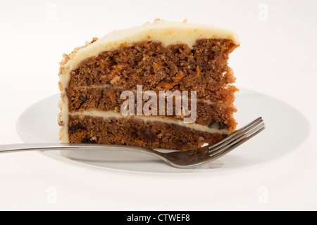 Fetta di torta di carote su una piastra bianca con una tavola forchetta - luminoso con una profondità di campo ridotta Foto Stock