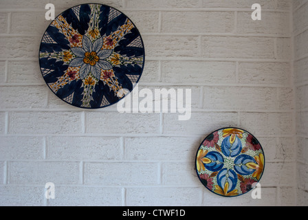 Due round di piatti decorativi montato sul dipinto di bianco di un muro di mattoni Foto Stock