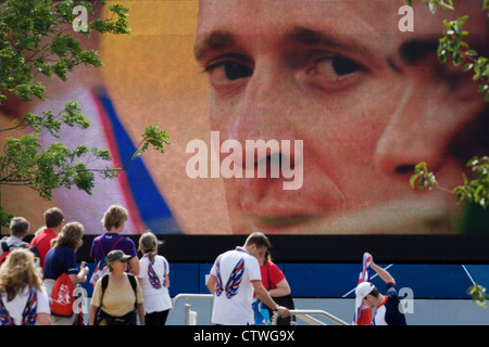 Close-up del Team GB il campione olimpico di ciclismo Bradley Wiggins su un grande schermo TV durante le Olimpiadi di Londra 2012. Wiggins è diventato un eroe per i Britannici con 'Wiggo's'' la vittoria nella prova a tempo del giorno precedente. Questa terra è stata trasformata in un 2.5 sq km complesso sportivo, una volta che le imprese industriali ed ora sede di otto luoghi di interesse tra cui il principale arena, Aquatics Centre e Velodromo plus degli atleti del Villaggio Olimpico. Dopo le Olimpiadi, il parco è noto come Queen Elizabeth Olympic Park. Foto Stock