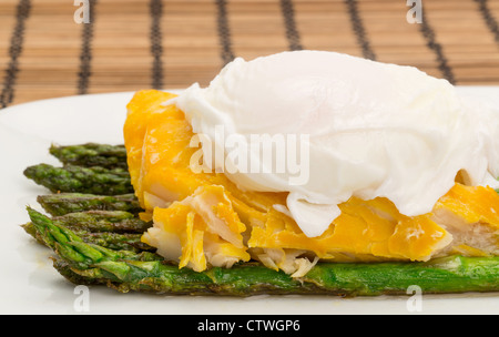 Close-up shot di eglefino affumicato, asparagi e un uovo in camicia la cena disposti su una piastra di cina Foto Stock