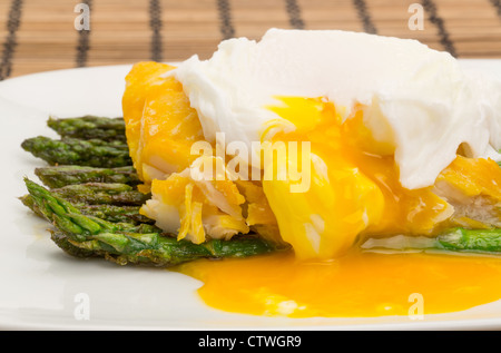 Close-up shot di eglefino affumicato, asparagi e un uovo in camicia la cena disposti su una piastra di Cina con il tuorlo scarico Foto Stock