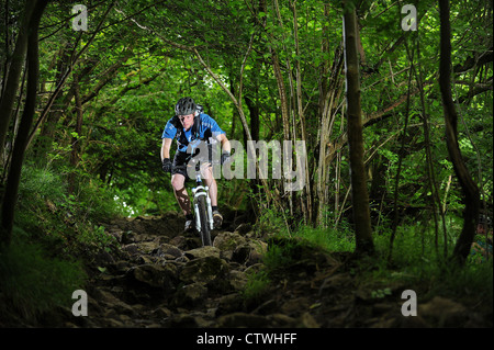 Un mountain biker cavalca un sentiero roccioso nei pressi del villaggio di Cheddar in Somerset sul bordo meridionale di Mendip Hills. Foto Stock