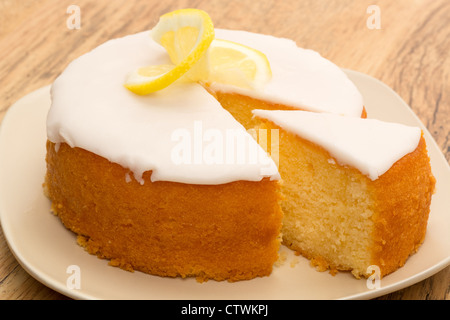 Un limone intero pioggerella torta con una fetta presa out. Foto Stock