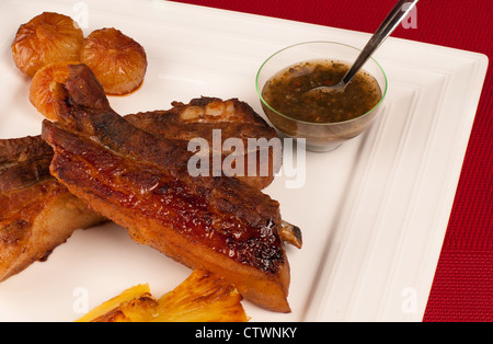 Caramellato alla griglia costolette di maiale servito con guarnire e argentino salsa chimichurri Foto Stock