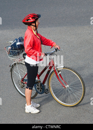 Donna ciclista in rosso brillante giacca e casco di sicurezza - Francia. Foto Stock
