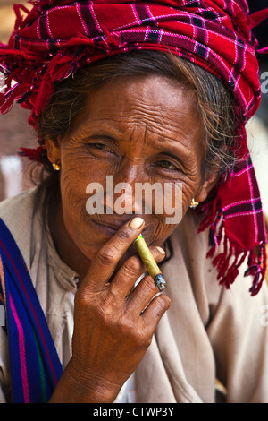 Una donna SHAN fuma un sigaro al mercato YWAMA sul modo di INDEIN - Lago Inle, MYANMAR Foto Stock