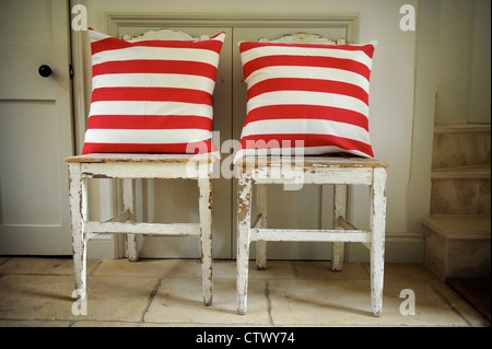Vecchio invecchiato Sedie in legno con moderno rosso e bianco striato cuscini REGNO UNITO Foto Stock